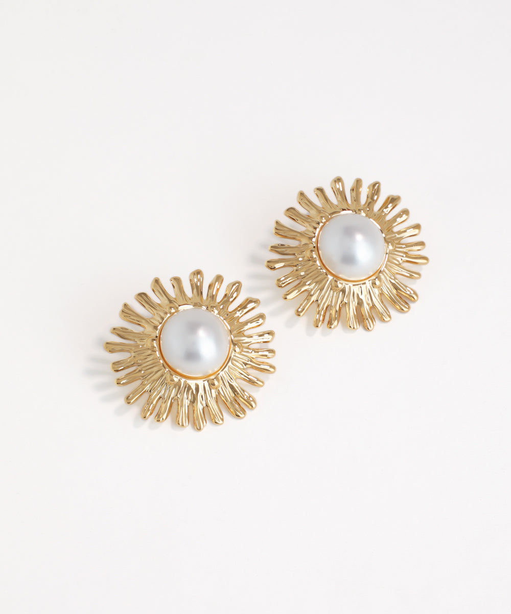 Gold earrings with pearl centers on a white background