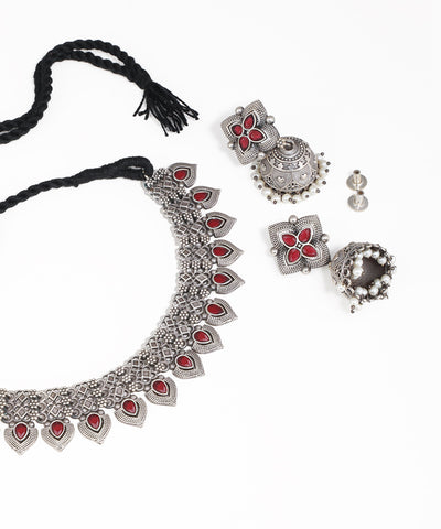 Silver jewelry set with red stones on a white background