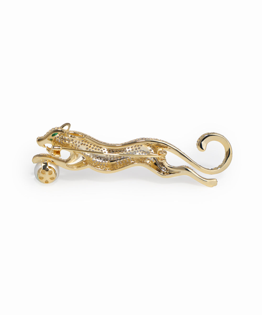 Gold panther brooch with green gemstone on a white background