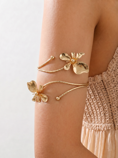 Gold floral arm cuffs on a person's arm with a neutral background