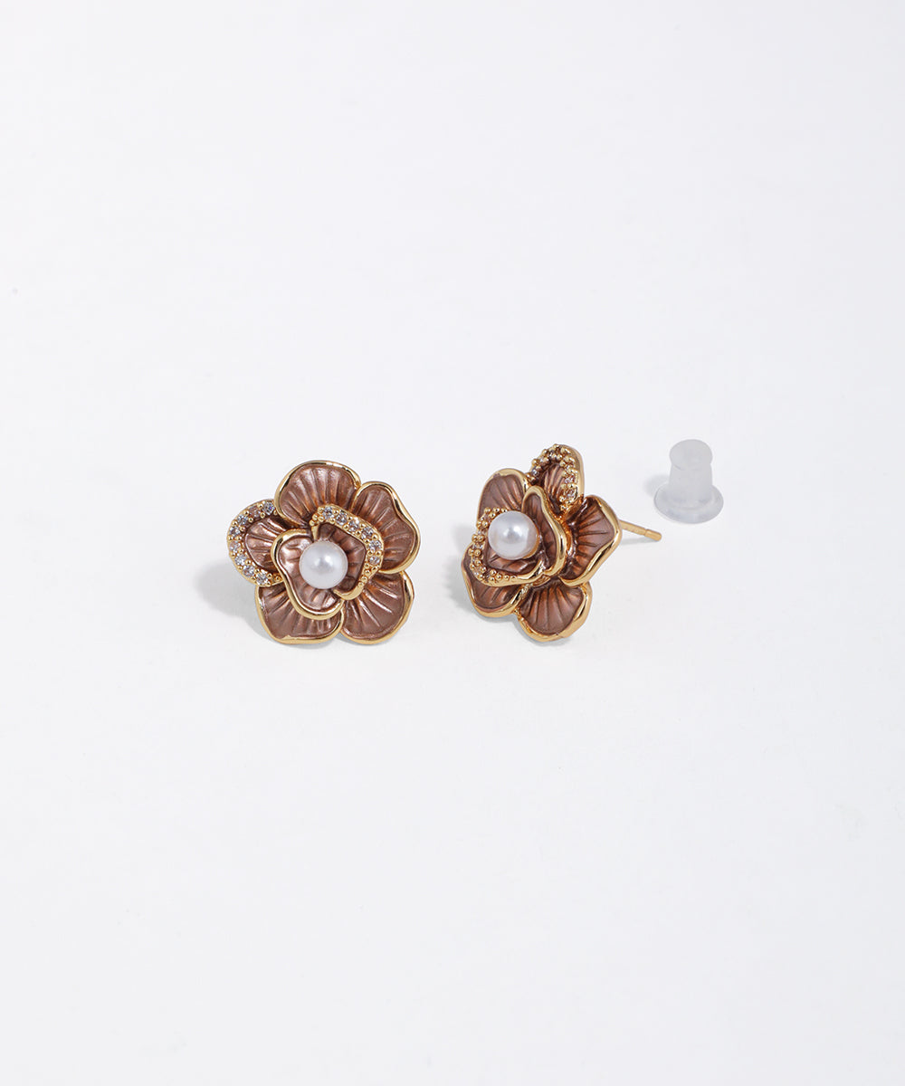 Gold-tone floral stud earrings with brownish-mauve petals, clear stones, and a central faux pearl.