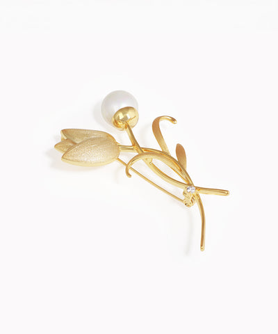 Gold-tone brooch with a sculpted tulip design, featuring a faux pearl bud, textured metal flower, and a clear stone.