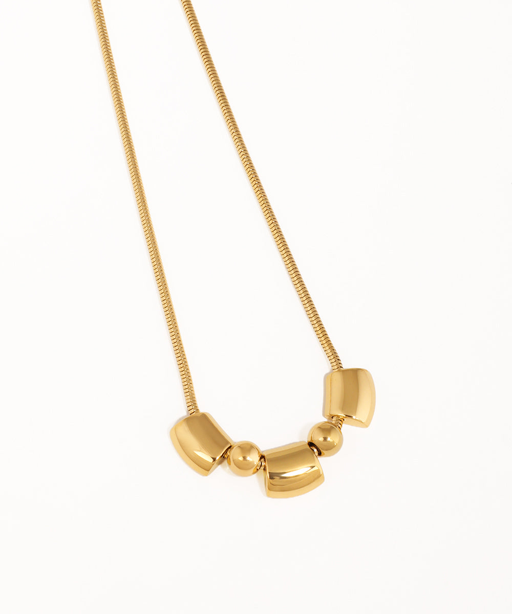Gold necklace with geometric pendant on a white background