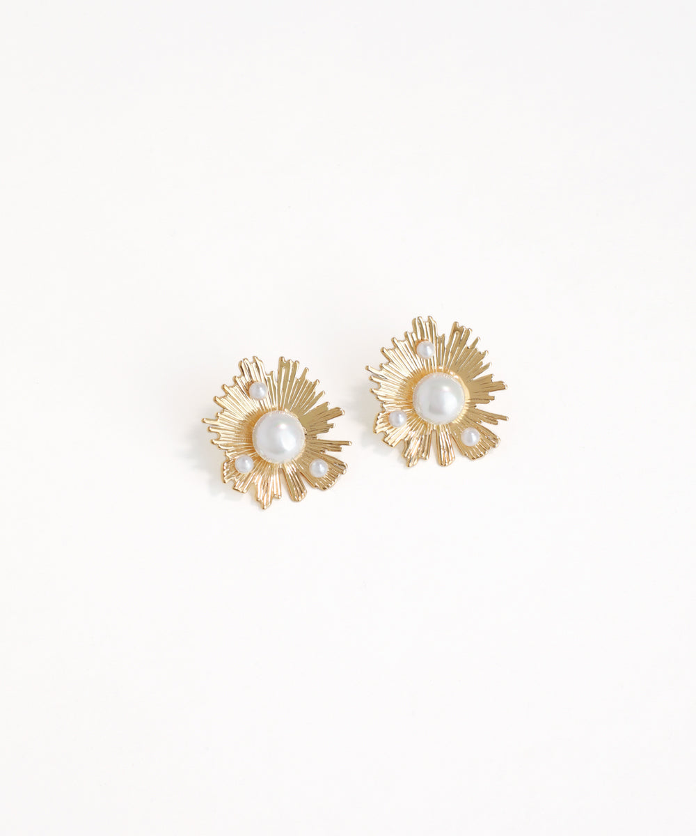 Gold earrings with pearl-like centers on a white background
