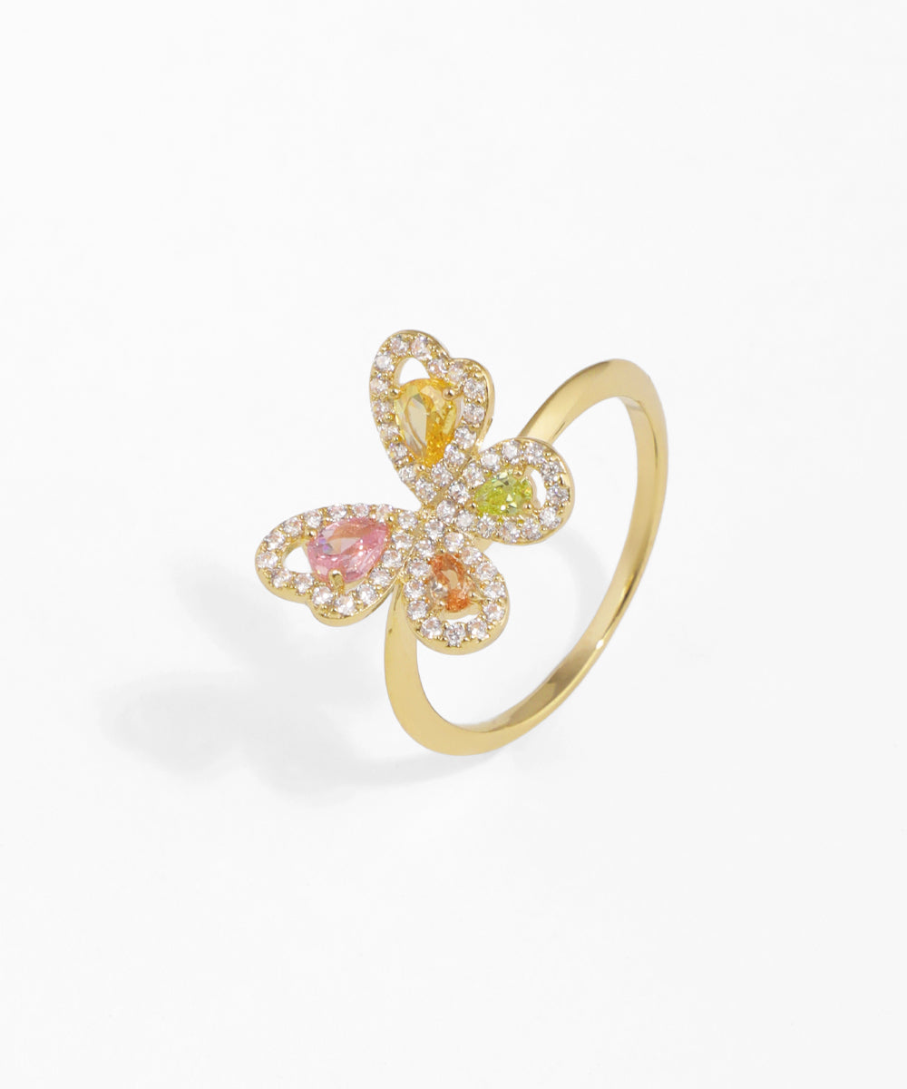 Gold-tone ring with a butterfly design, featuring clear and colorful cubic zirconia stones in pink, orange, yellow, and green.