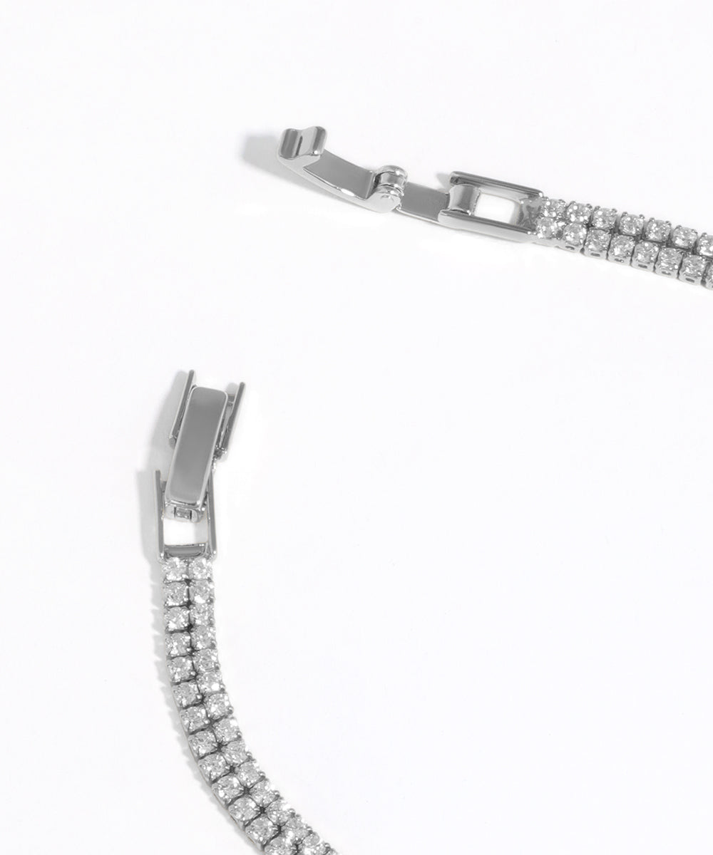 Close-up of a silver bracelet with clear gemstones on a white background