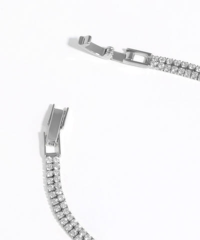 Close-up of a silver bracelet with clear gemstones on a white background