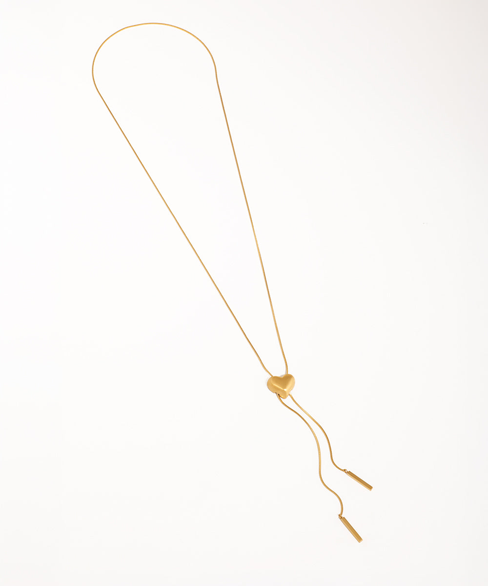 Gold-tone lariat necklace with a matte heart slider and bar tassels on a smooth chain