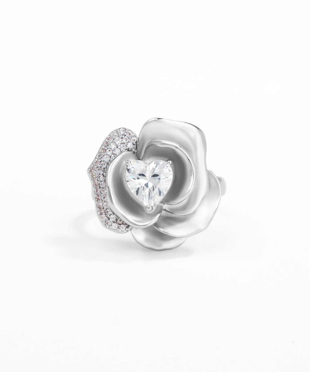 Silver flower-shaped jewelry piece with a heart-shaped gem on a white background