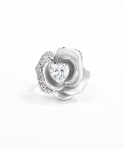 Silver flower-shaped jewelry piece with a heart-shaped gem on a white background