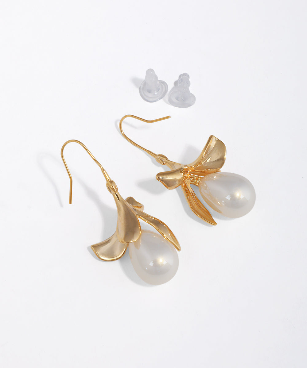 Matte gold-tone drop earrings with sculptural petal design and teardrop faux pearl