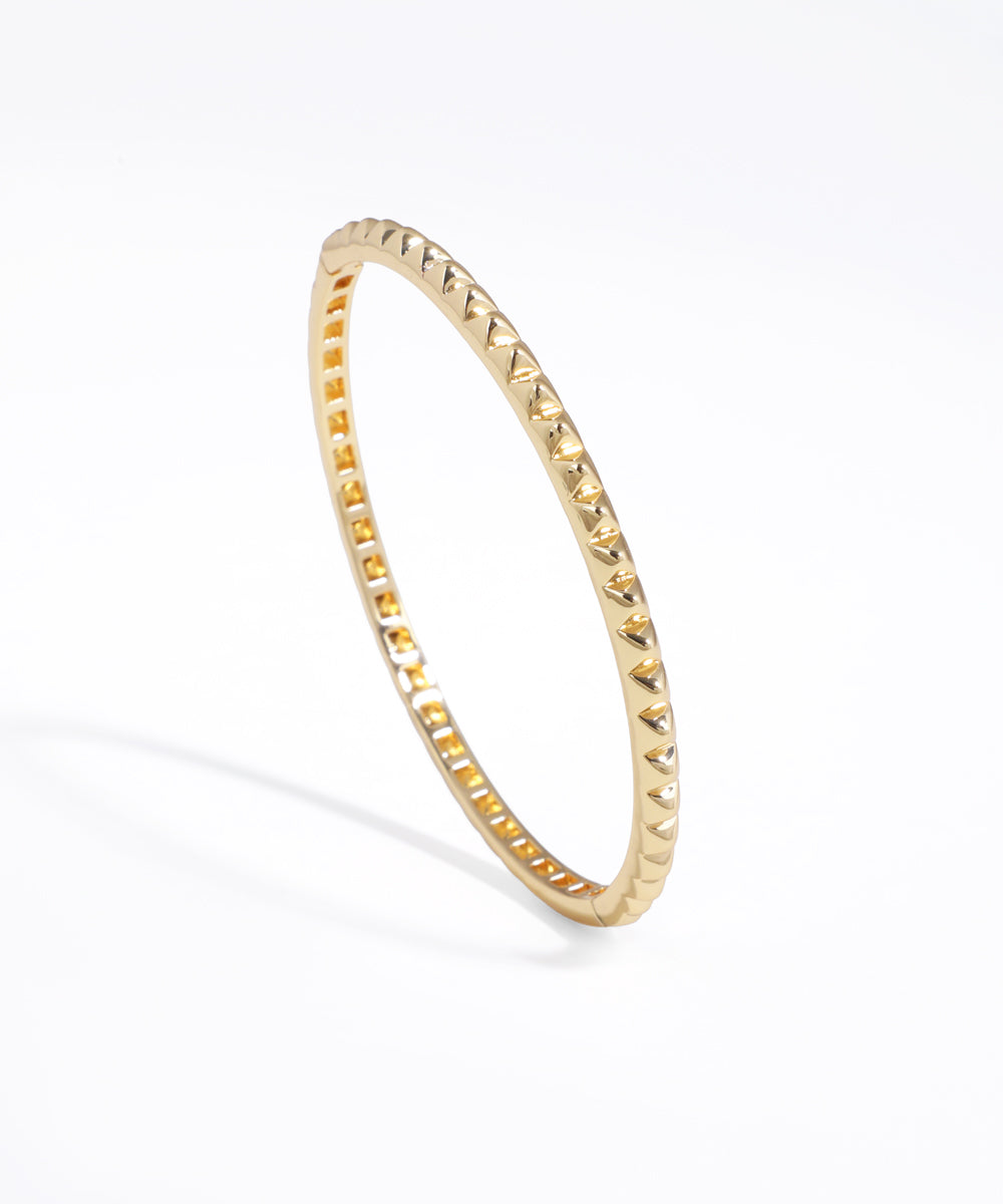 Gold-tone bracelet with all-over geometric pyramid studs and a shiny finish.