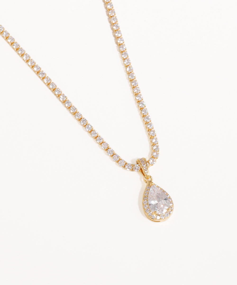 Gold necklace with a teardrop-shaped diamond pendant on a white background