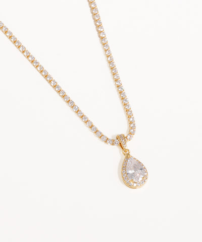 Gold necklace with a teardrop-shaped diamond pendant on a white background