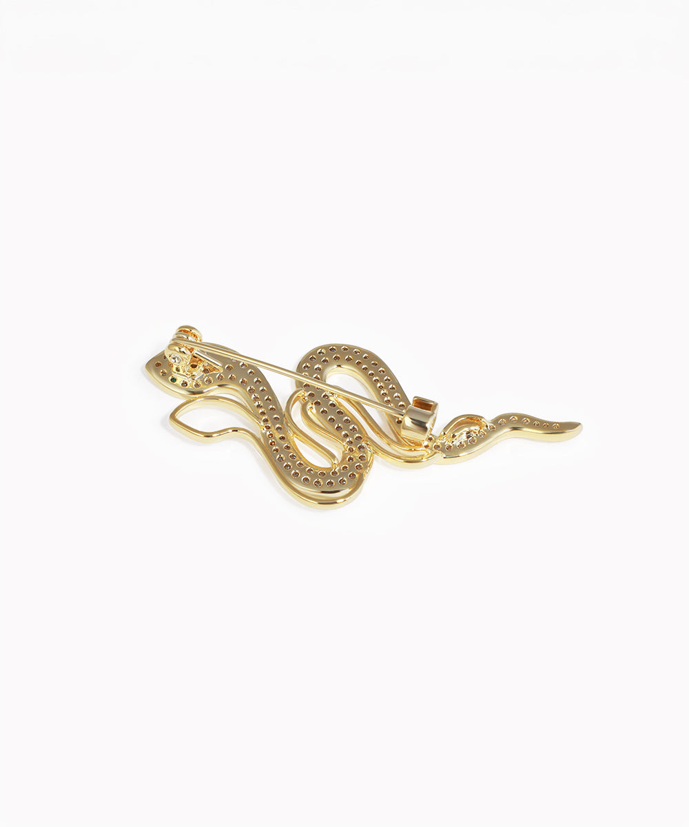 Gold snake-shaped brooch on a white background