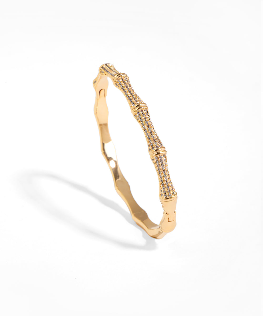 Gold-tone bracelet with bamboo segments, half pavé-set with clear CZ stones and a hinged closure.