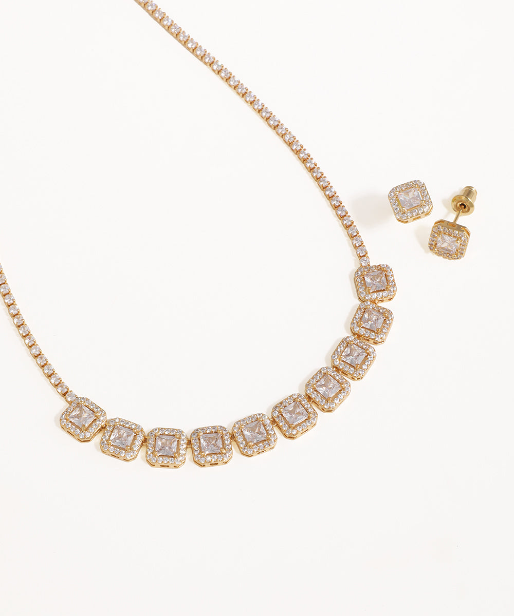 Gold necklace and earrings with clear gemstones on a white background