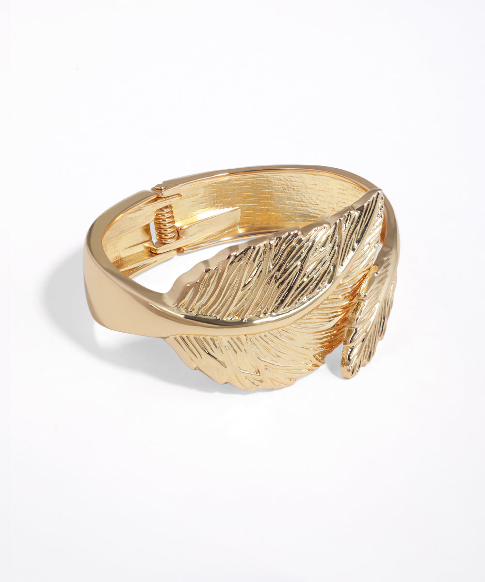 Gold feather-shaped ring on a white background