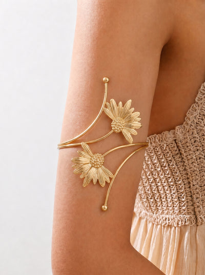 Gold floral arm cuff on a person's arm with a neutral background