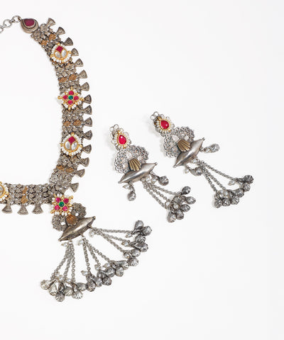 Ornate necklace and earrings set on a white background
