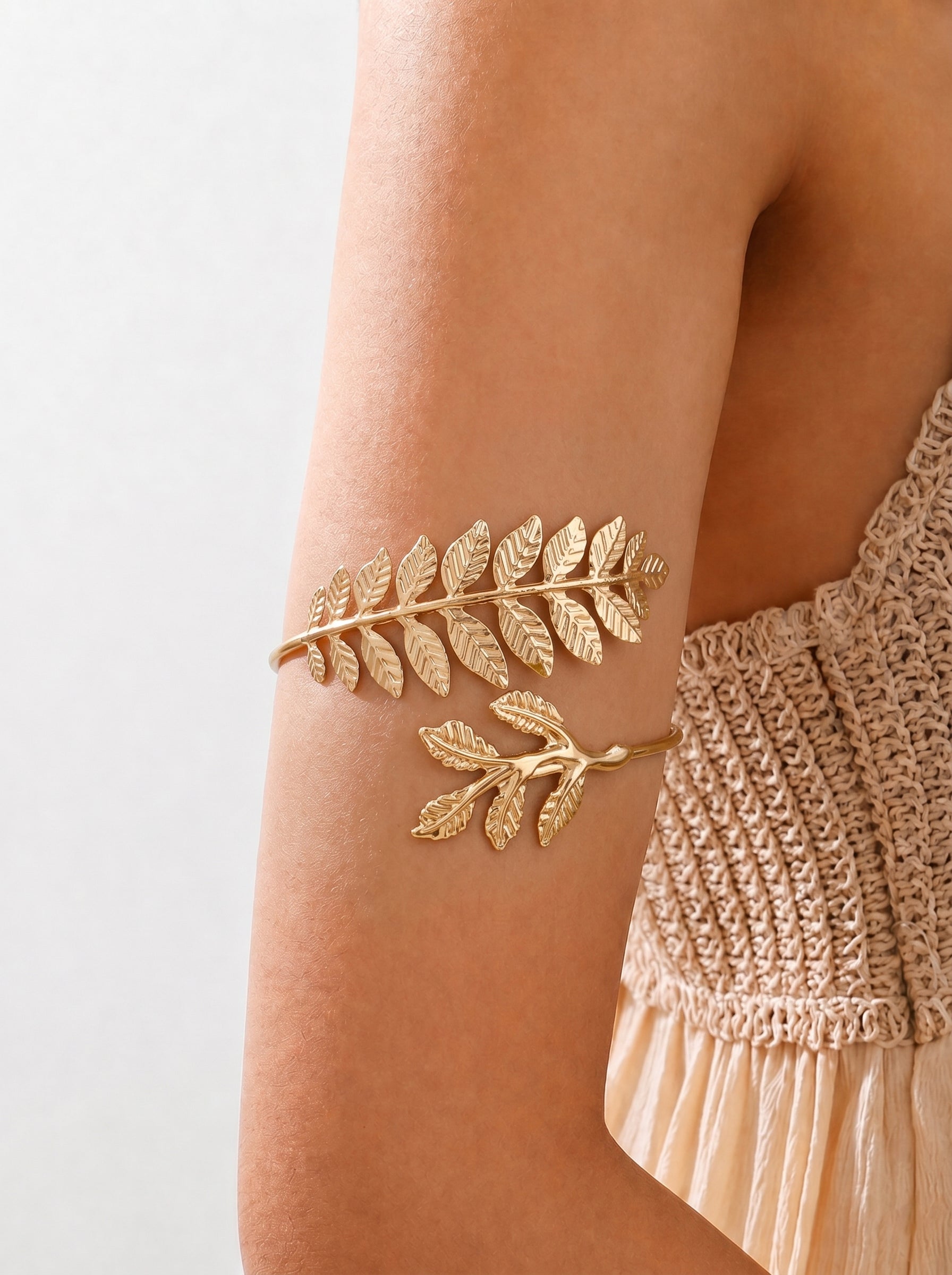 Gold leaf arm band on a person's arm with a neutral background