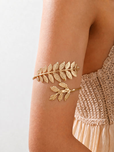 Gold leaf arm band on a person's arm with a neutral background