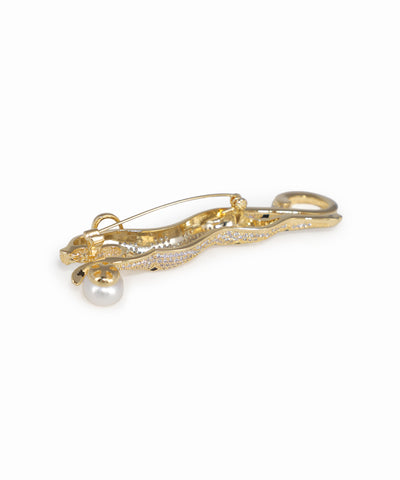 Gold brooch with a pearl on a white background