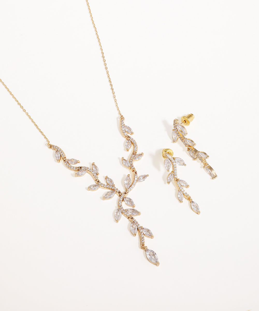 Gold necklace and earrings with leaf design on a white background