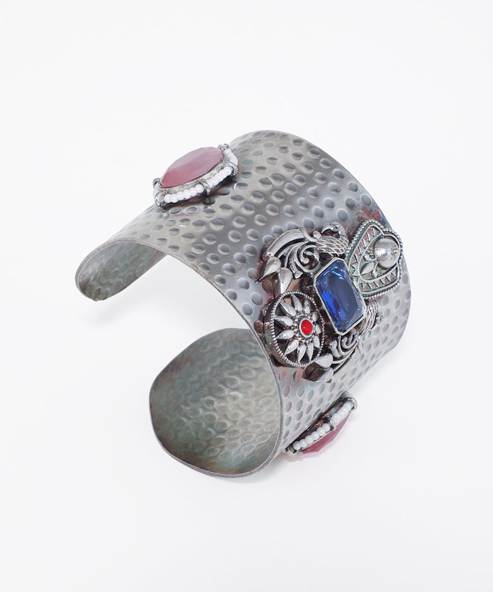 Oxidise cuff bracelet with hammered texture and intricate settings of pink, blue, and red stones with white accents.