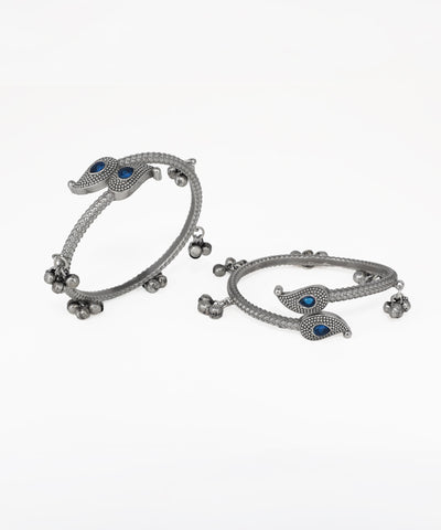 Pair of silver bangles with blue stones on a white background