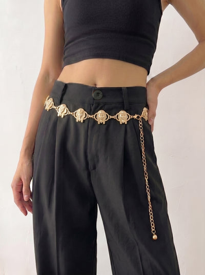 Person wearing black pants with a gold chain belt on a white background