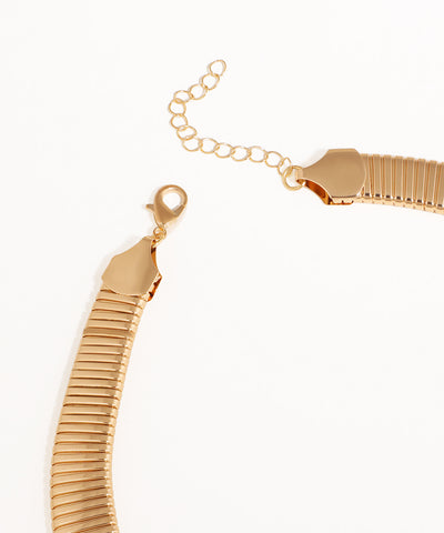 Gold bracelet with a textured design on a white background
