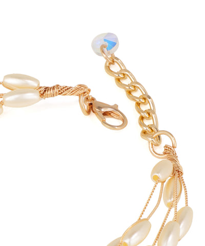 Gold bracelet with pearl-like beads on a white background