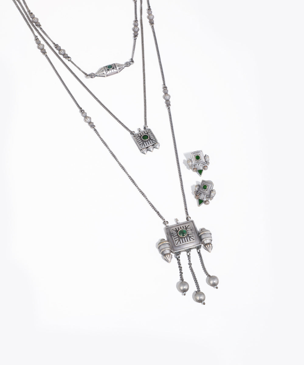 Silver necklace with green gemstones on a white background