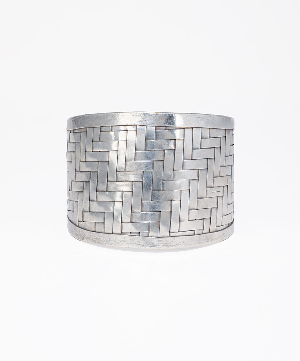 Silver cuff bracelet with a herringbone pattern on a white background