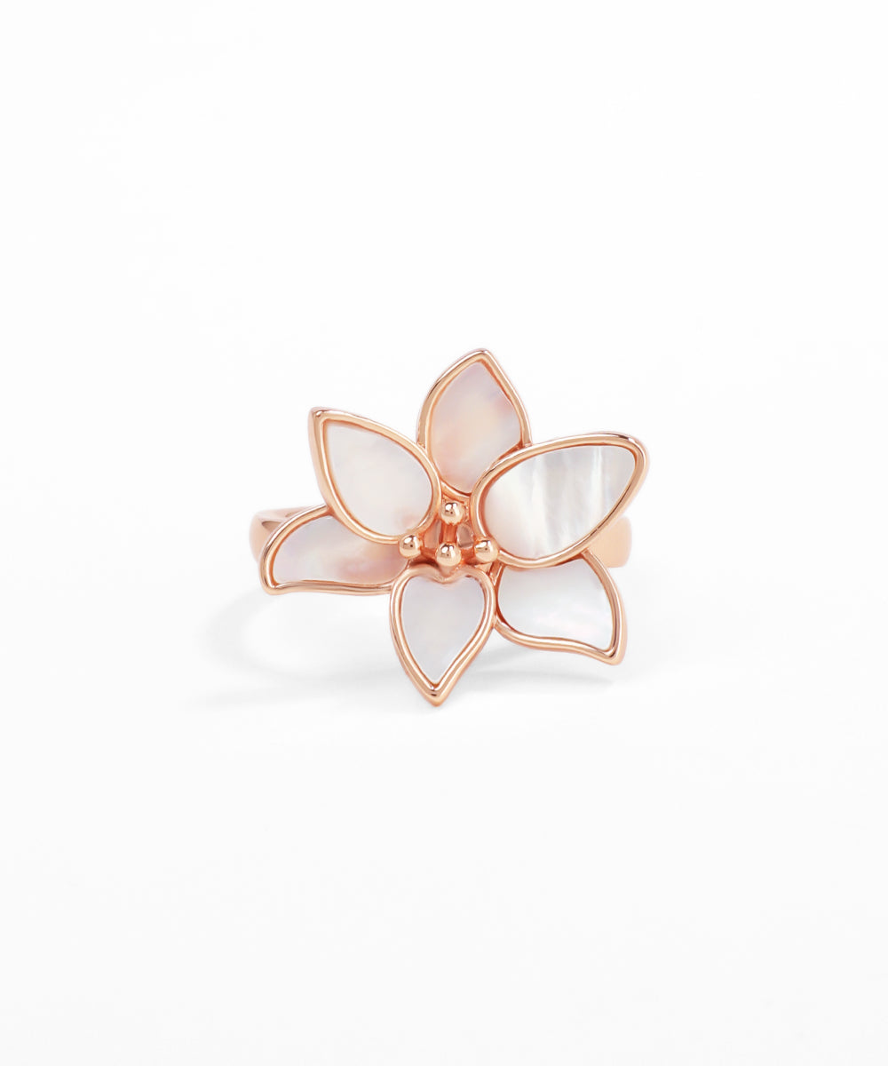 Rose gold ring with a white floral design on a white background