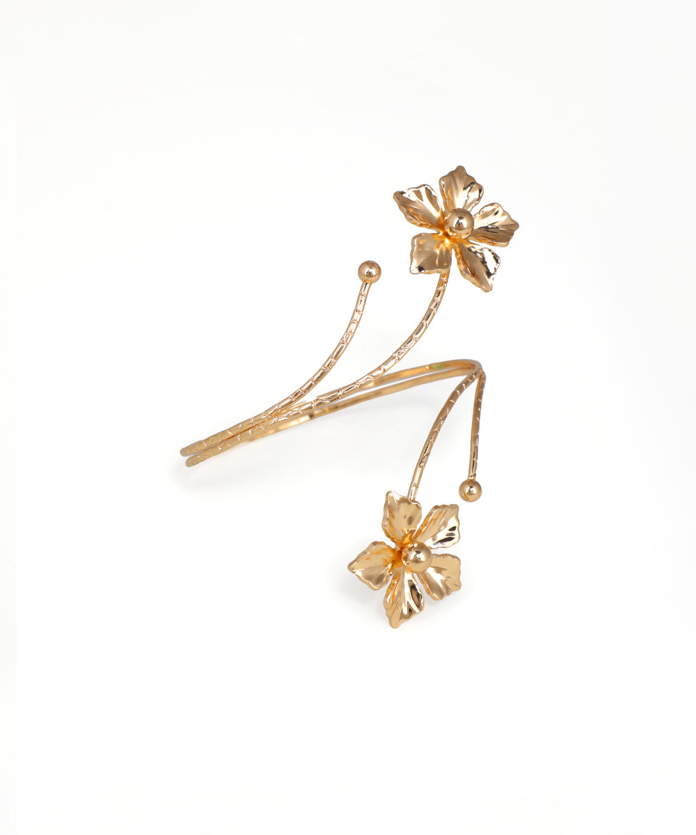 Gold-tone arm cuff with sculpted floral motifs and winding metal design.