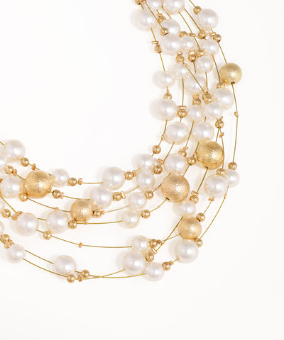 Multi-strand pearl and gold bead necklace on a white background