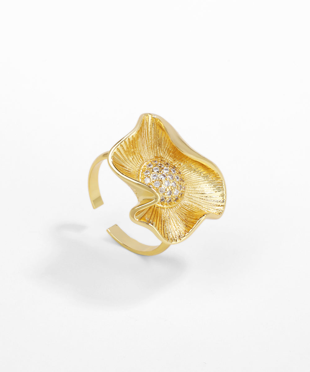 Gold ring with a floral design and embedded stones on a white background