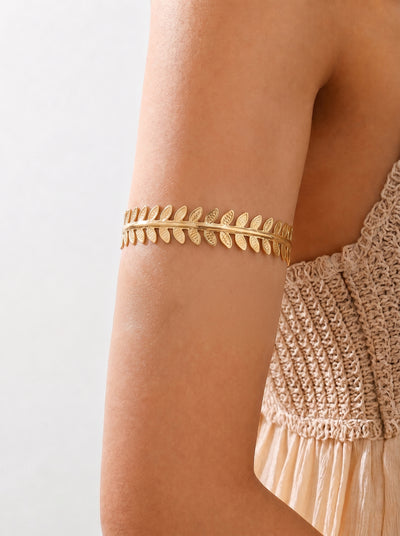 Gold arm cuff on a person's arm with a neutral background
