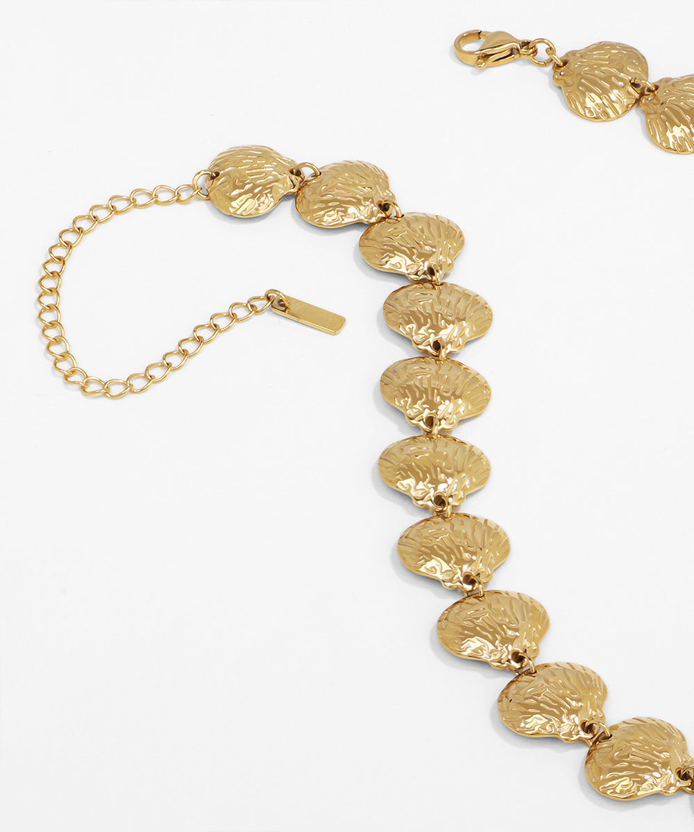 Gold bracelet with leaf-like links on a white background