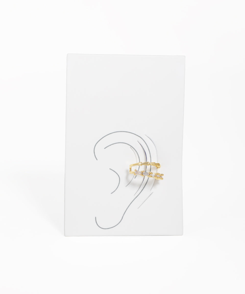 Gold ear cuff on a white card with an ear illustration