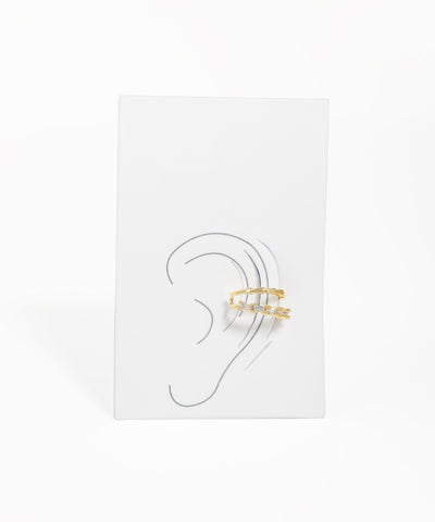 Gold ear cuff on a white card with an ear illustration