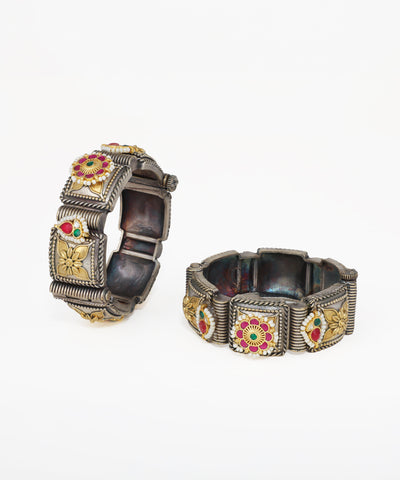 Pair of ornate bracelets with floral designs on a white background