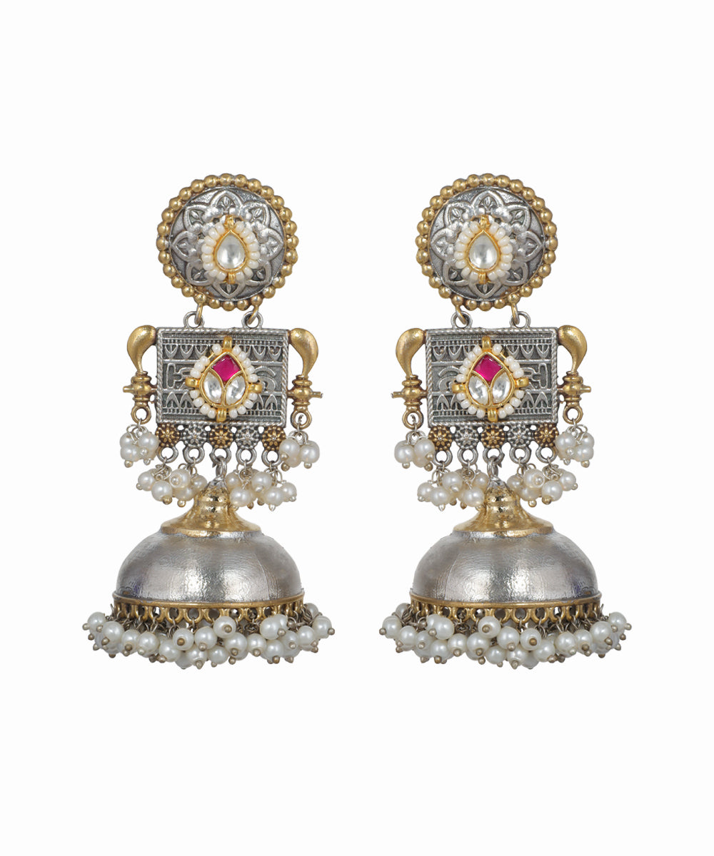 Pair of ornate earrings with pearls and gemstones on a white background