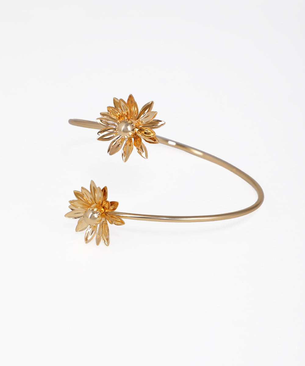 Gold bracelet with floral designs on a white background