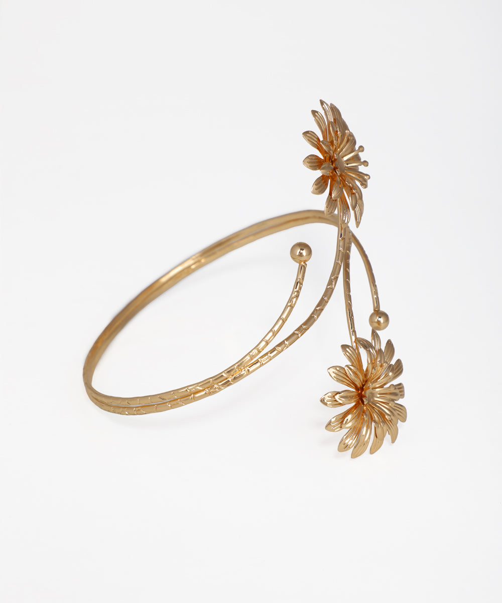 Gold bracelet with floral designs on a white background