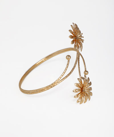 Gold bracelet with floral designs on a white background