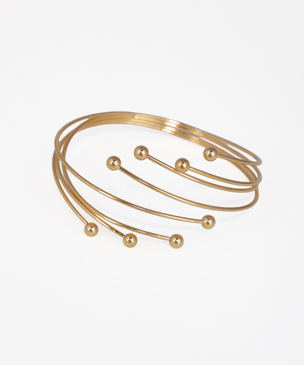 Gold bracelet with spherical accents on a light gray background