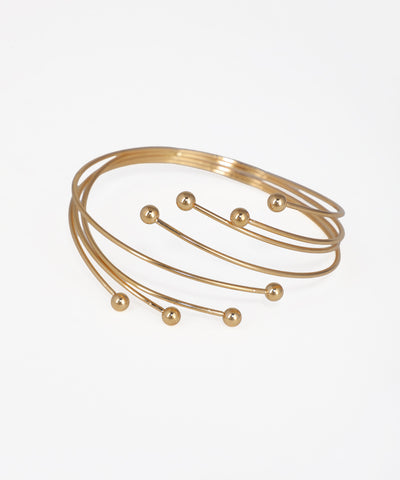 Gold bracelet with spherical accents on a light gray background